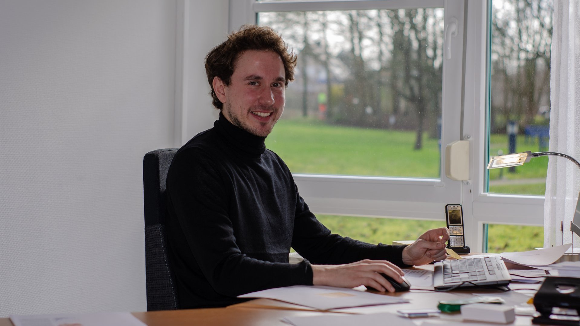 Quartiersmanager Frederik Lauwen am Schreibtisch sitzend lächelt er dem Betrachter zu